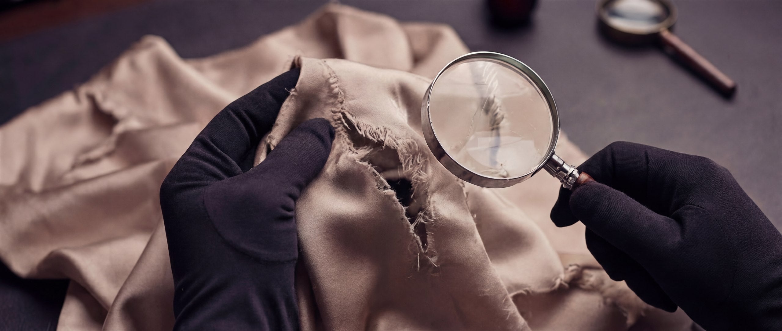 A repair specialist assessing material wear with magnification.