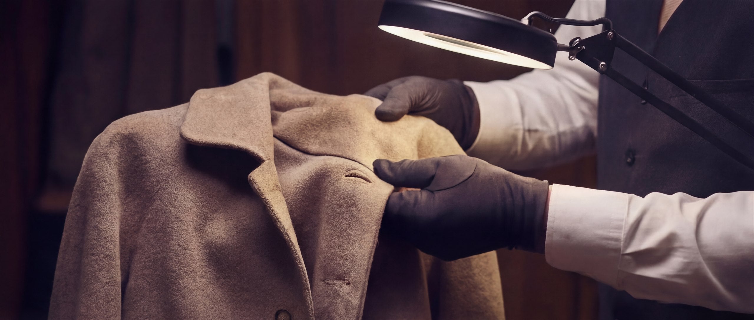 A repaired garment undergoing final quality control under focused atelier light.