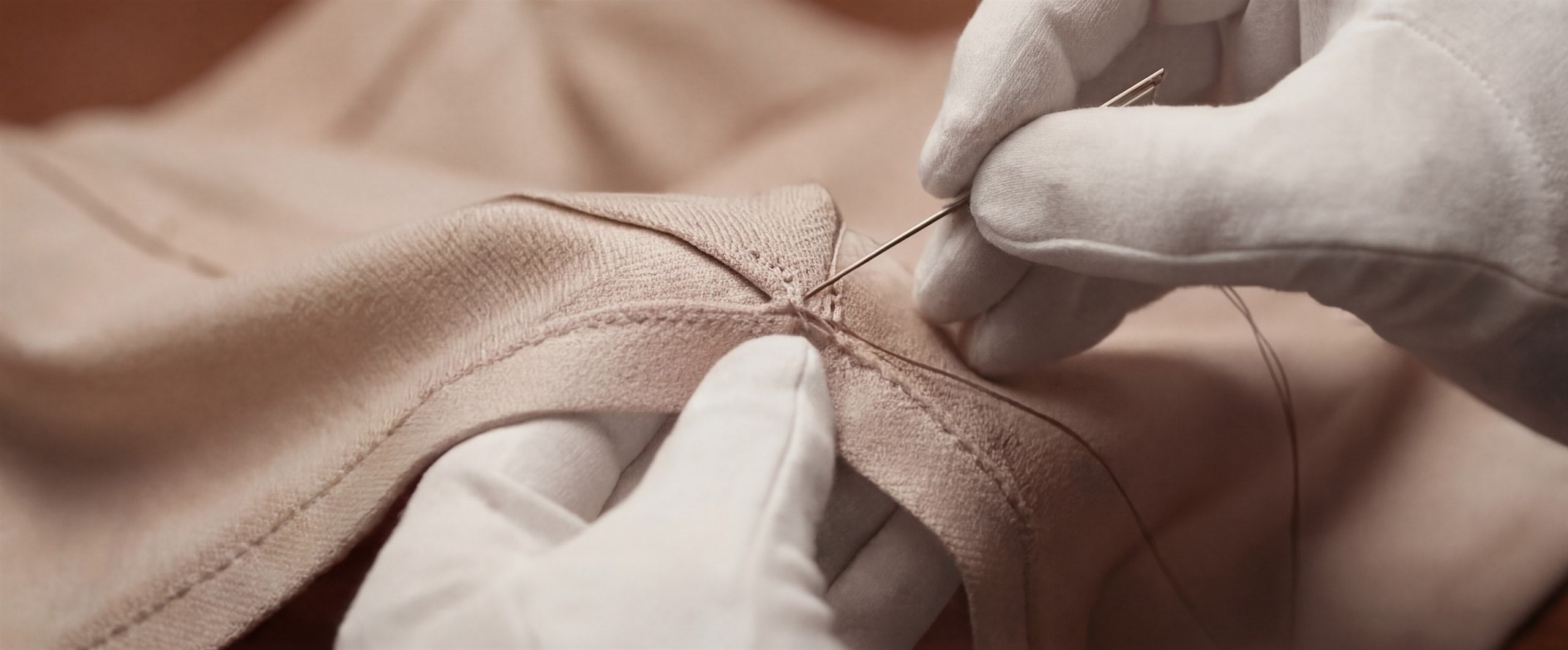 Gloved hands preserving a textile surface through careful pressure and handling.